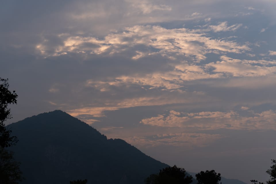 黄昏天空云层透出暖光，山峰呈深色剪影