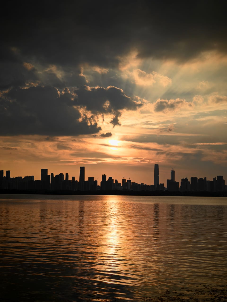 云隙夕照下的江面与城市天际线倒影